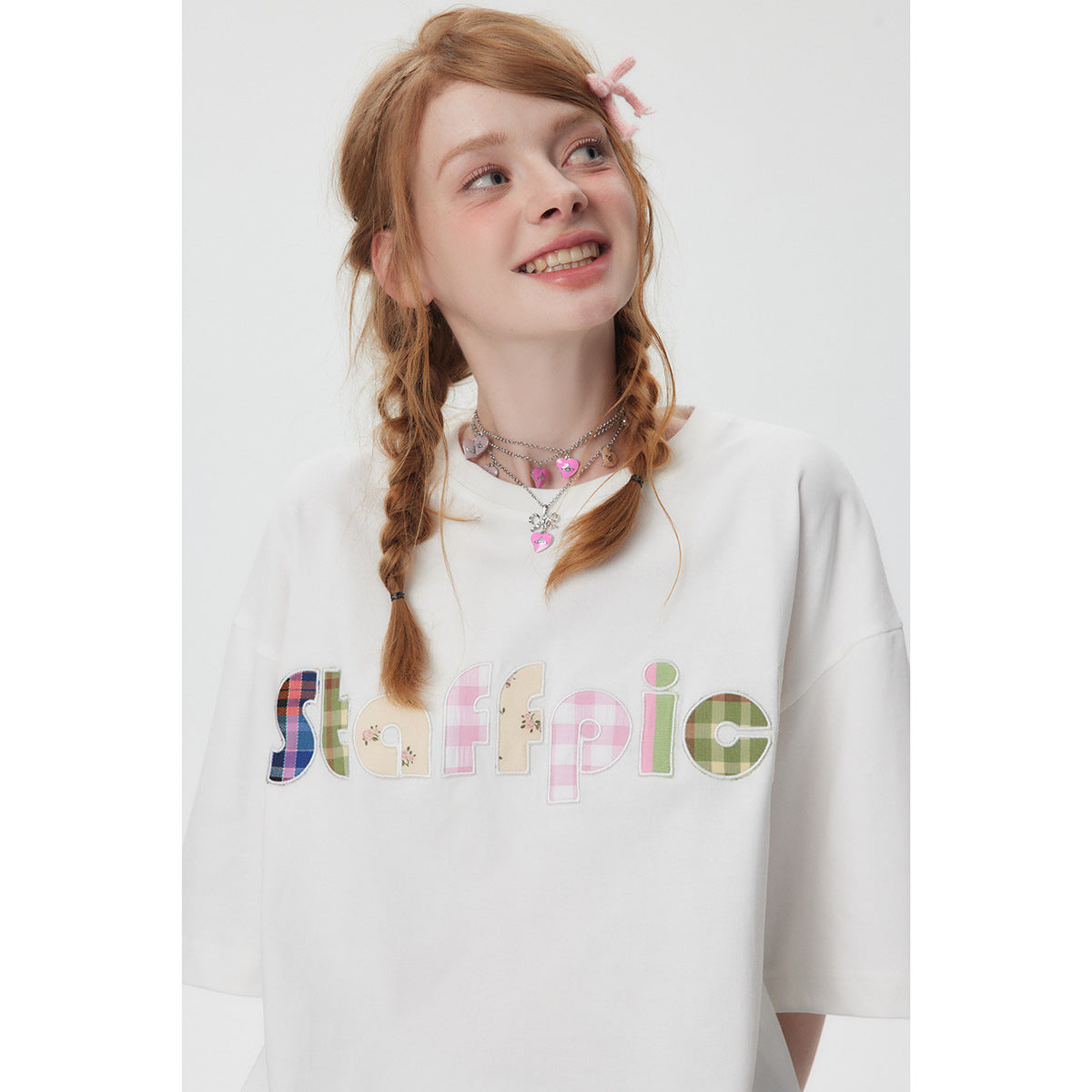 Close view of a model wearing an oversized white T-shirt with colorful patchwork lettering across the chest.