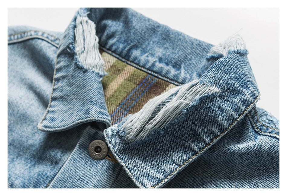 Close-up of a light blue denim jacket collar with frayed edges and plaid lining.