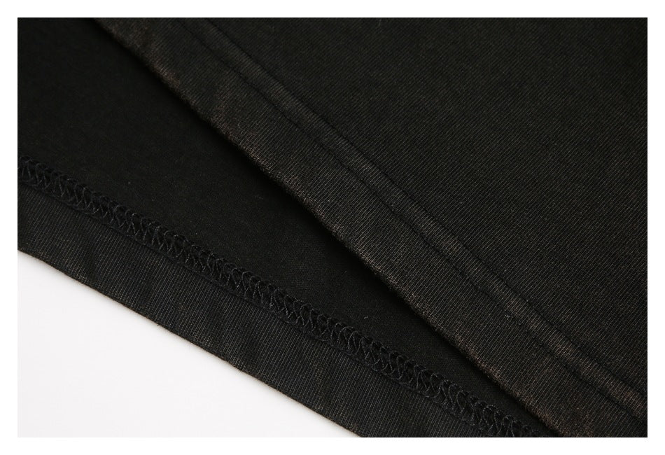 Close-up of a black garment's folded edge and overlock stitching.