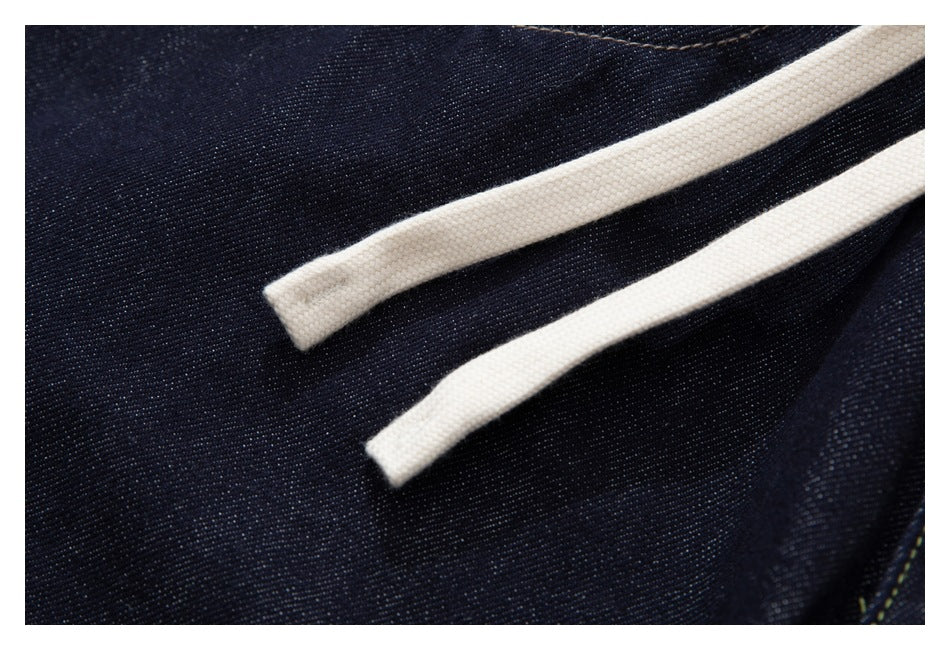 Two white drawstrings lie across the dark indigo denim of the jeans.