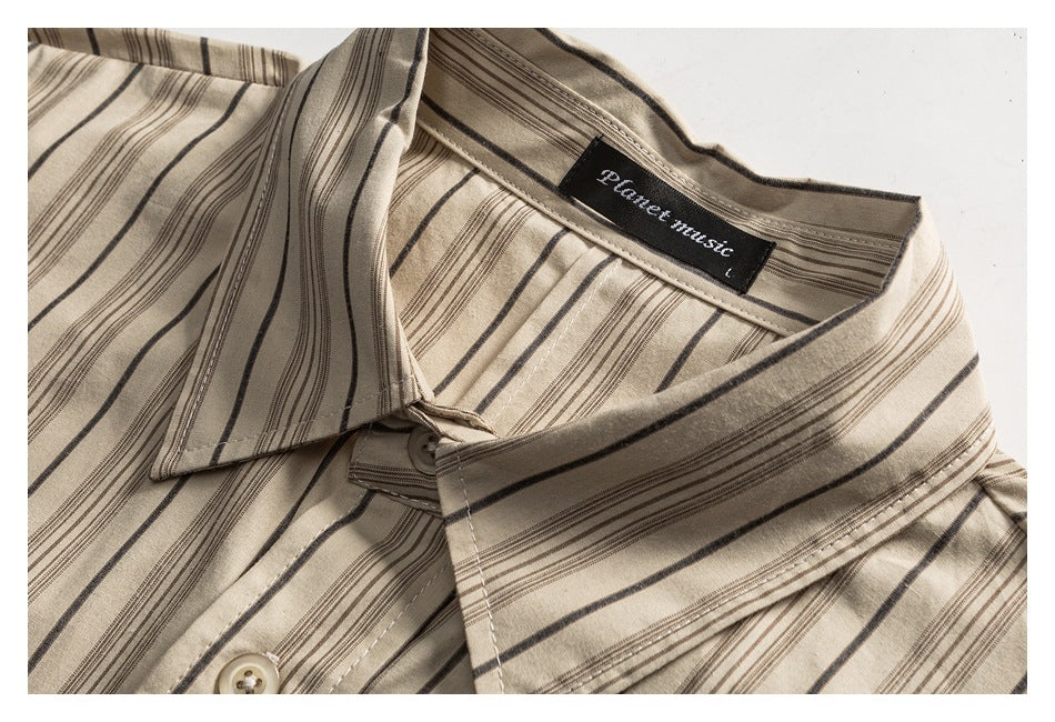 Close-up of a cream shirt's pointed collar, striped fabric, and inner neck label.