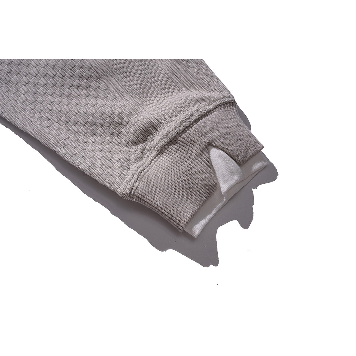 Close-up of a light gray textured sleeve ending in a ribbed cuff, with a white inner layer visible.