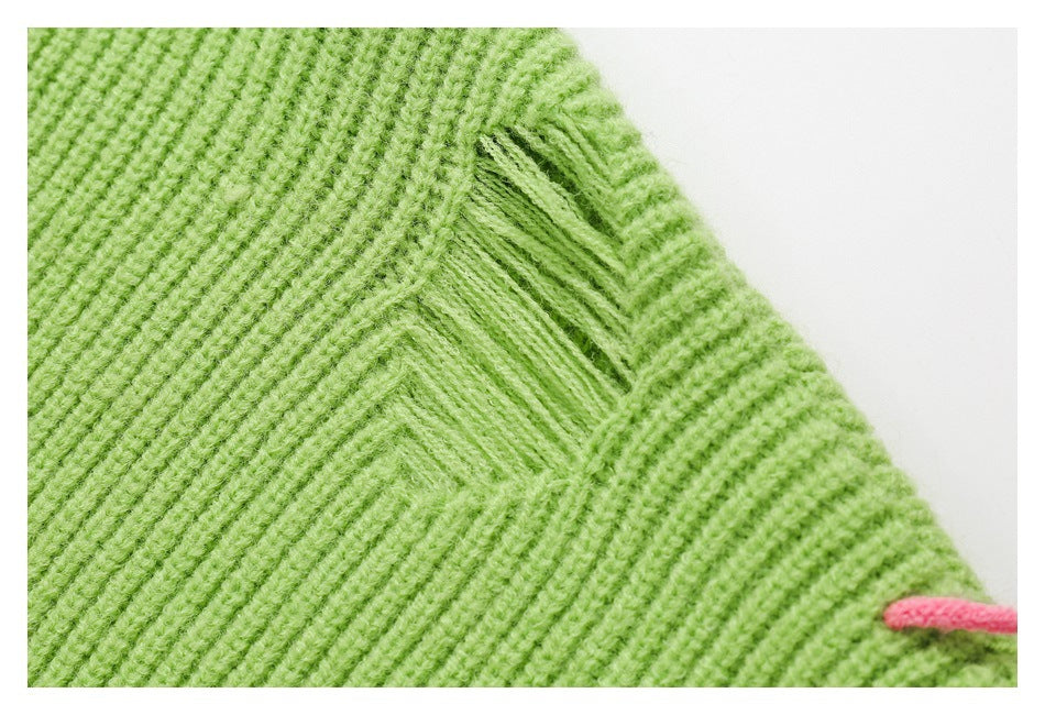 Close-up of lime-green ribbed knit with a diagonal seam and a small pink embroidered accent.