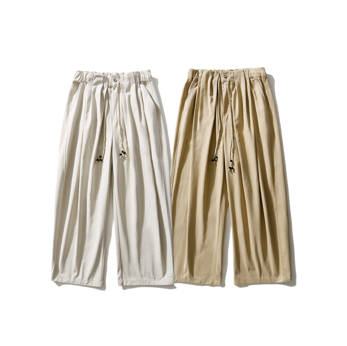 Front view of two pairs of pleated wide-leg pants with drawstrings, in ivory and tan.