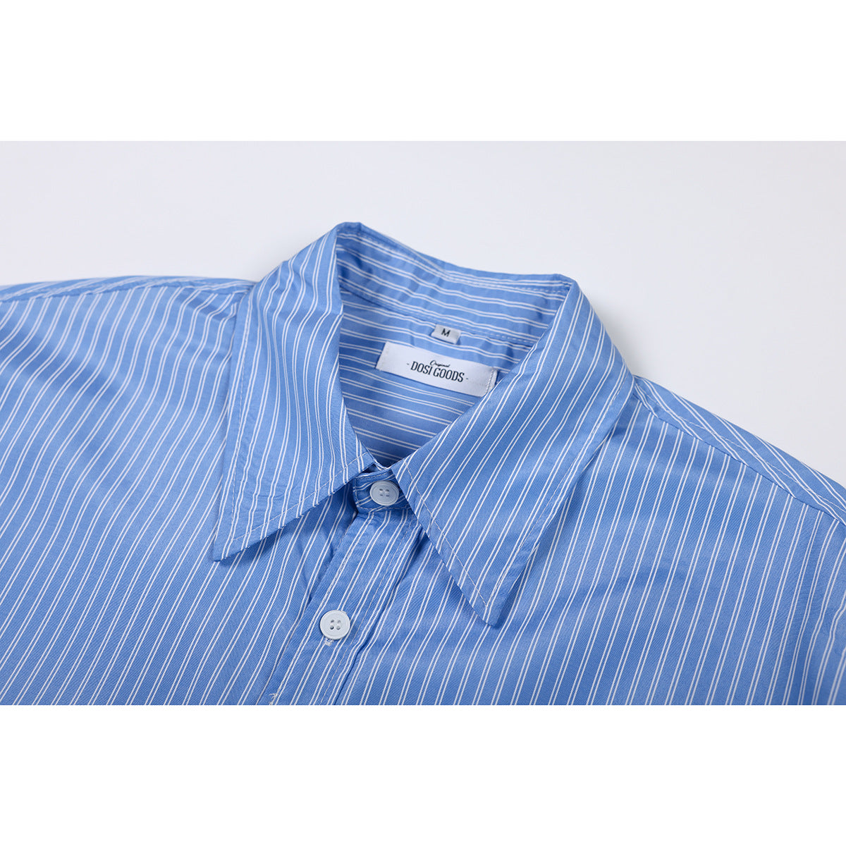 Close-up of a blue shirt with thin white stripes, pointed collar, and white buttons.
