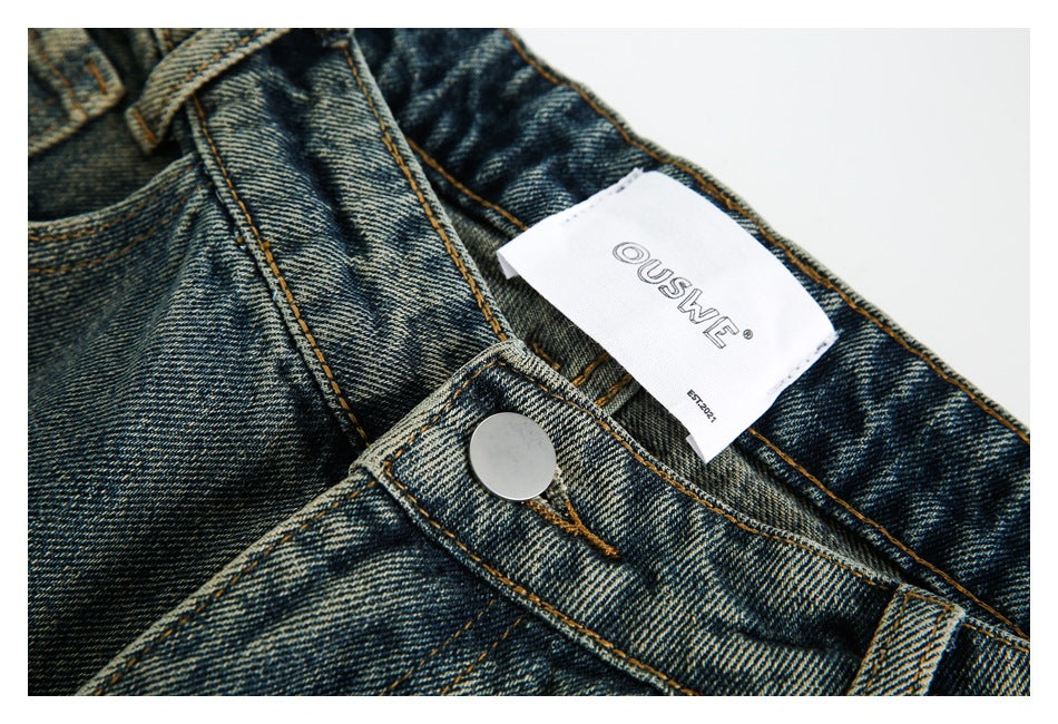 Close-up of the denim waistband, metal button, stitching, and white brand label.
