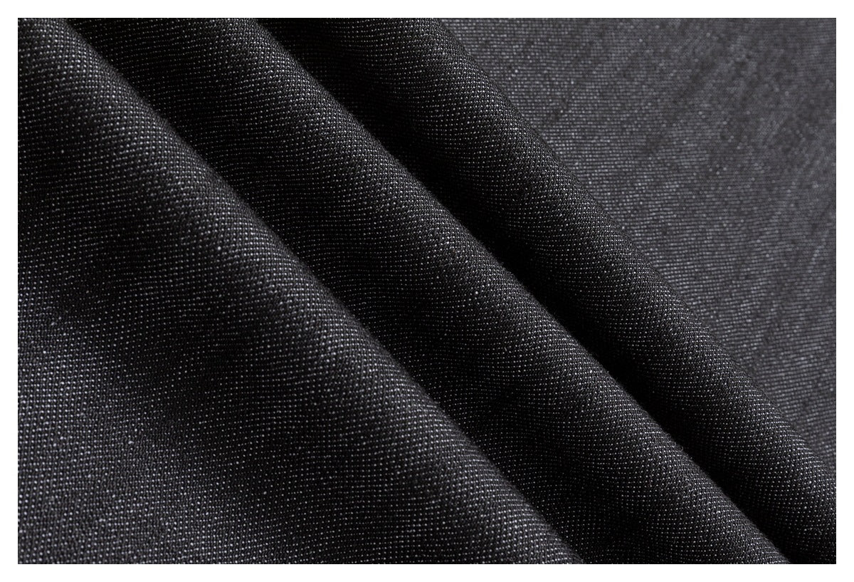 Close-up of dark charcoal fabric draped in folds, showing its fine surface texture.