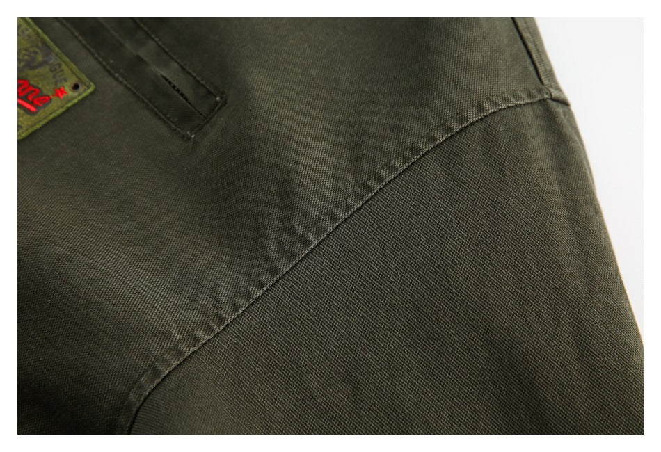Close-up of the olive jacket's curved stitched seam and textured fabric, with part of a patch visible.