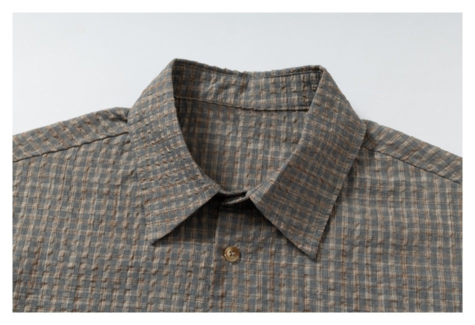 Framed close-up of a gray-brown plaid shirt collar and top button.