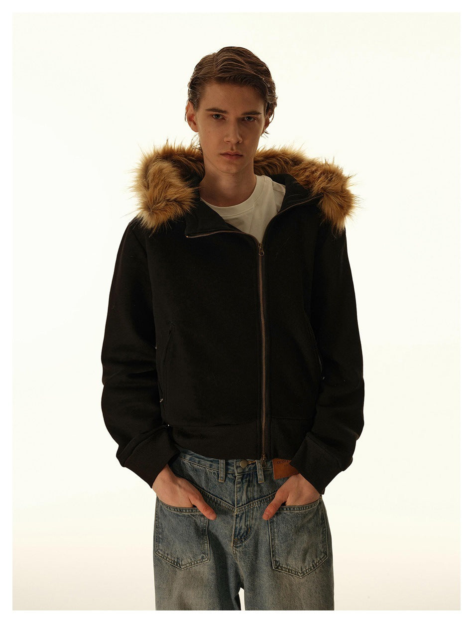 Model wearing a black hooded zip jacket with tan fur-style hood trim over a white tee and light-wash jeans, front view