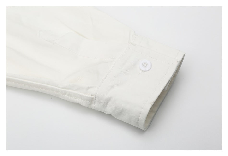 Close-up of an off-white shirt sleeve ending in a buttoned cuff.