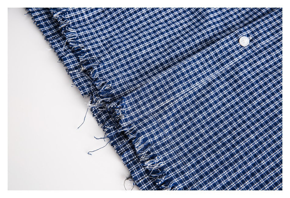 Close-up of navy and white checked fabric with a frayed edge and white button.