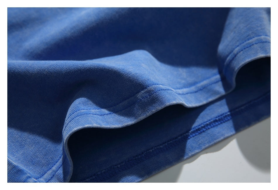 Close-up of the blue T-shirt's folded bottom hem and interior overlock stitching.