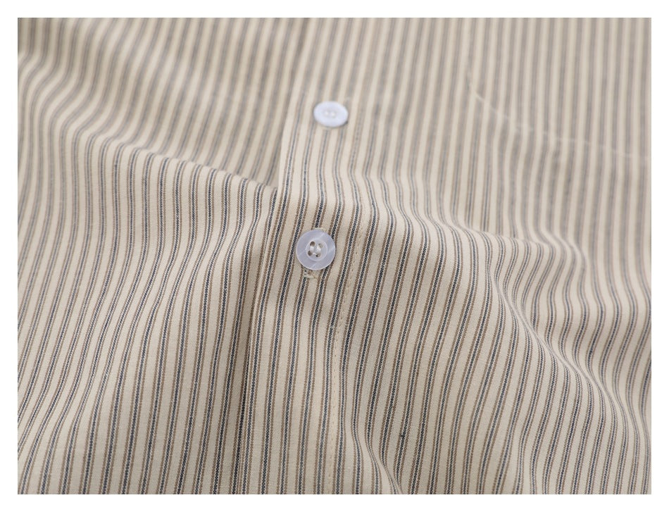 Close-up of white buttons on beige fabric with narrow brown and gray stripes.
