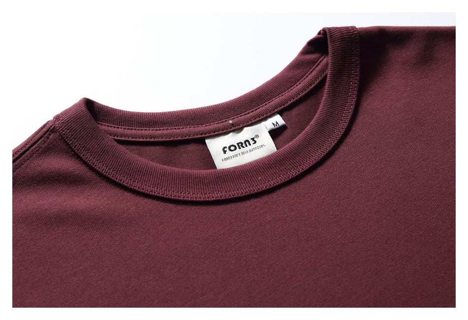 Close-up of a burgundy T-shirt's ribbed crew neckline and sewn label marked size M.
