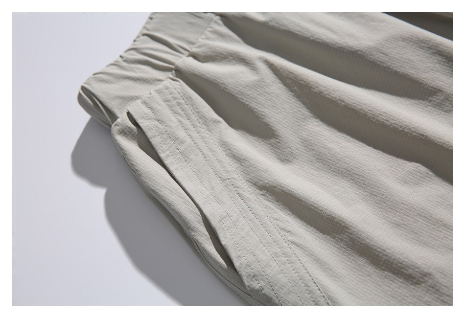 Close-up of a stitched pocket opening and seam on light gray-beige trousers.
