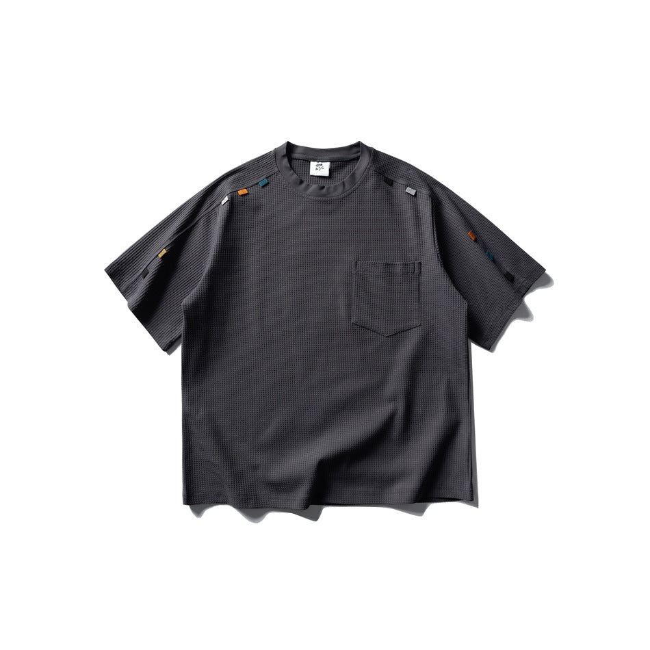 Dark gray waffle-knit short-sleeve T-shirt front with chest pocket and small colored tabs on shoulders and sleeves