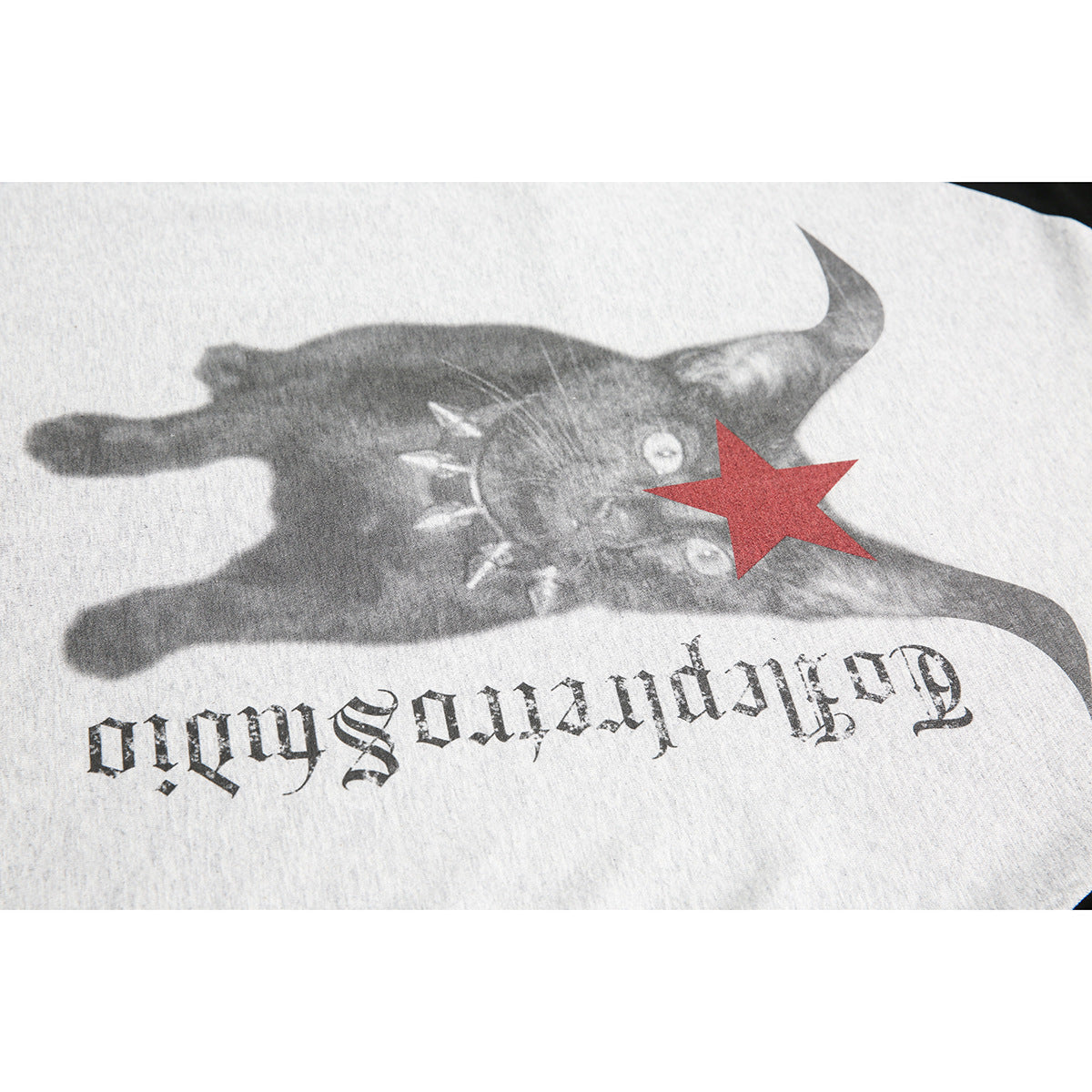 Close-up of a heather-gray shirt graphic with a dark animal face, red star, and upside-down gothic lettering.