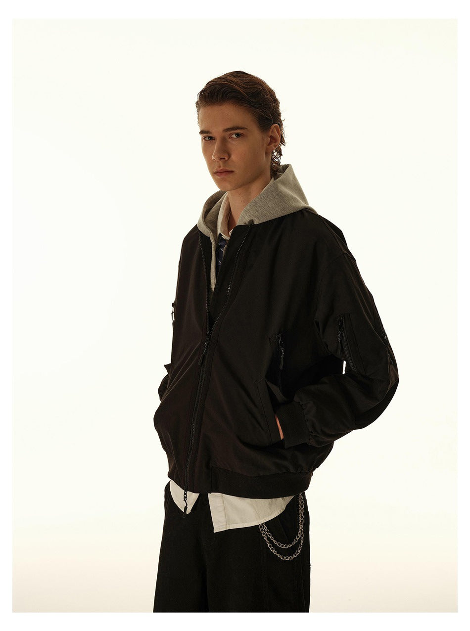 Close view of a model wearing a black bomber jacket with zip details, layered over a gray hooded top.