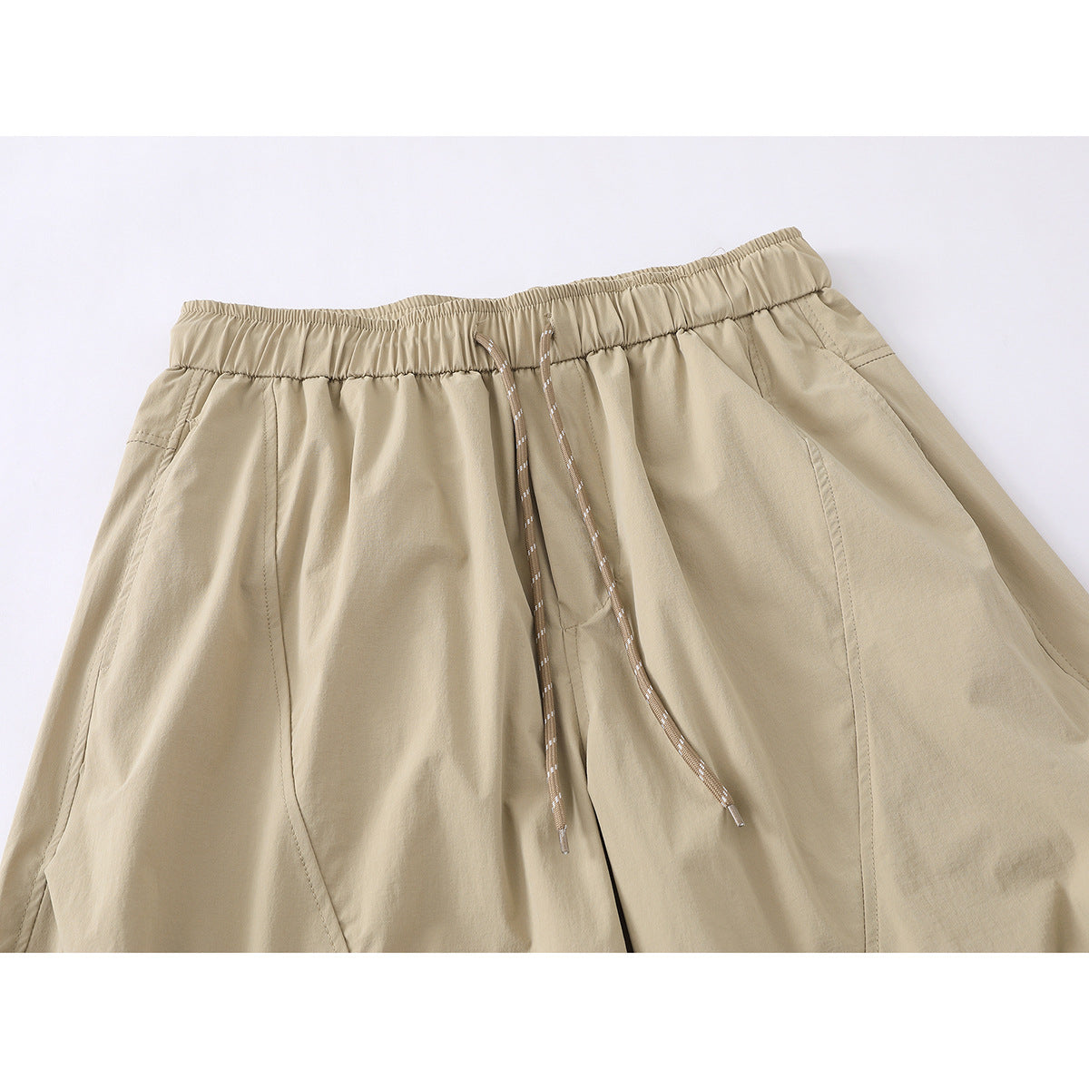 Close-up of beige wide-leg pants showing the elastic waistband, braided drawstrings and curved front seams.