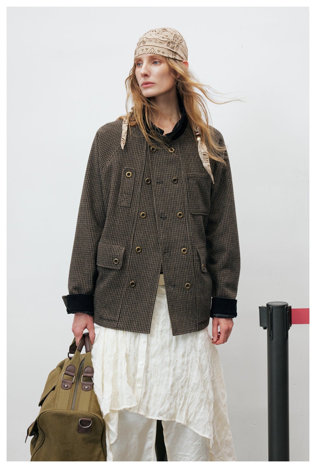 Model wearing a dark brown checked double-breasted jacket with black cuffs, shown from the front over a white skirt.