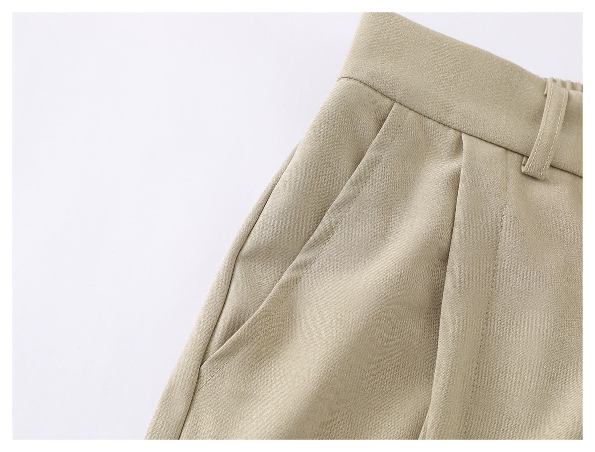 Close-up of beige trousers showing a slanted side pocket, waistband, belt loop, and pleat.