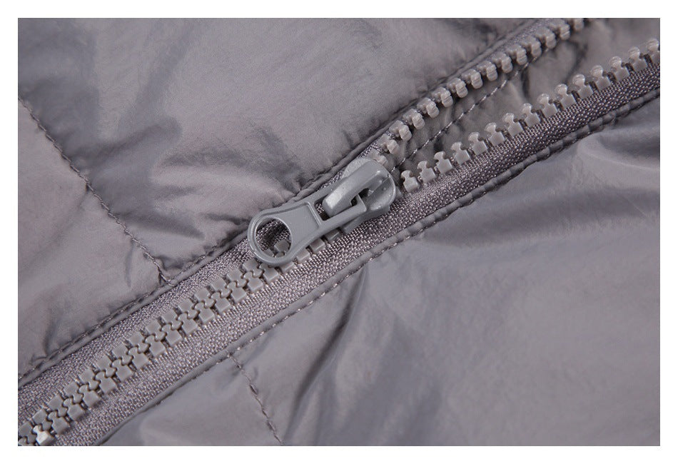 Close-up of a gray puffer jacket's chunky plastic zipper and stitched panels.