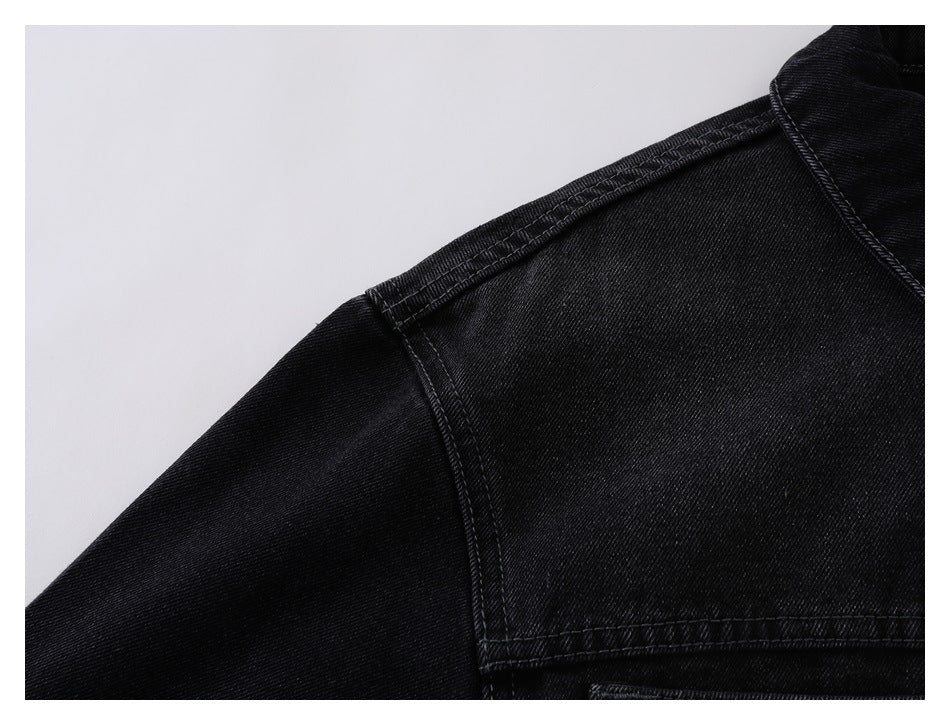Close-up of a black denim jacket shoulder seam and collar edge.