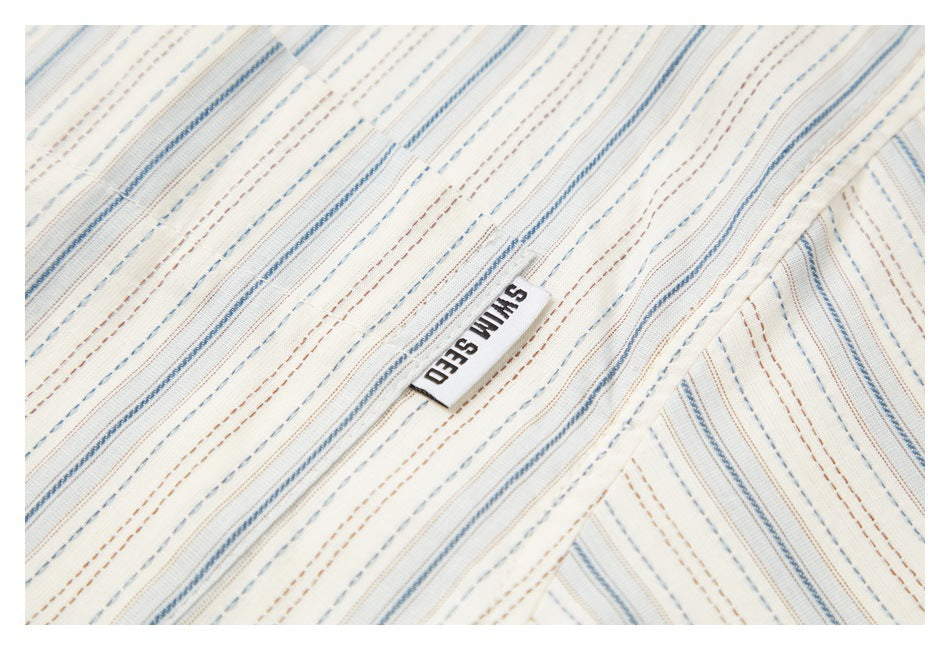 Close-up of striped cream fabric and a sewn white label reading “SHIN SEED.”