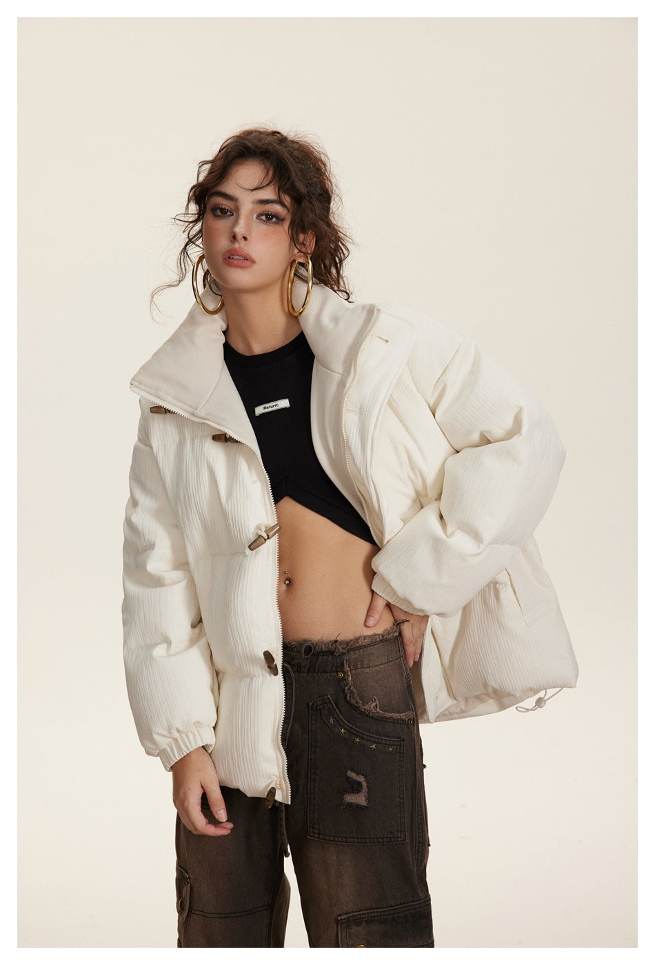 Model wearing an open ivory padded jacket with a high collar and wooden toggles, shown with a black crop top.