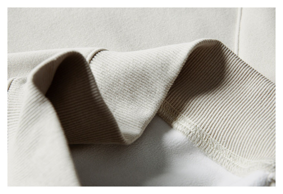 Close-up showing the cream sweatshirt's ribbed cuff and inside stitching.