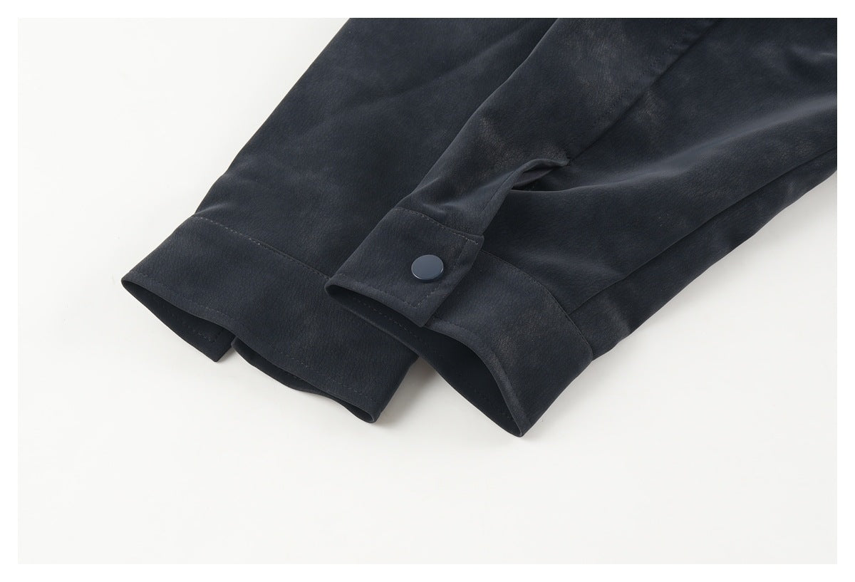 Close-up of a dark jacket sleeve cuff with an adjustable snap tab and stitched seams.