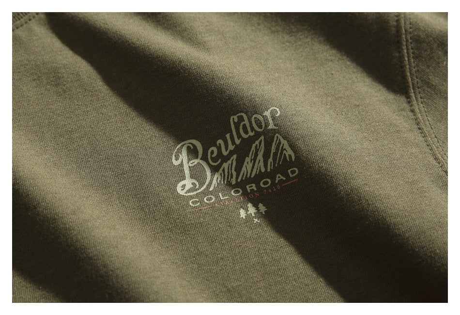 Close-up of a cream Colorado-themed graphic printed on olive green T-shirt fabric.