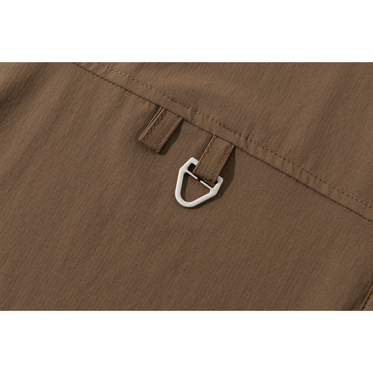 Close-up of a brown shirt with a small metal hook attached near a stitched seam.