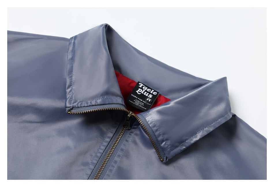 Close-up of a slate-blue jacket collar, red lining, and brass-toned zipper with a black neck label.