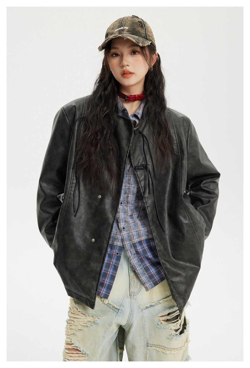 Front view of a model wearing a charcoal-black oversized jacket with frog closures and a blue plaid shirt.