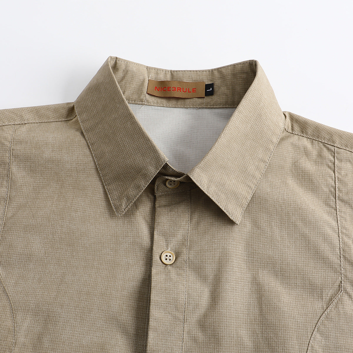 Close-up of a beige micro-check short-sleeve shirt collar, button placket, and neck label.