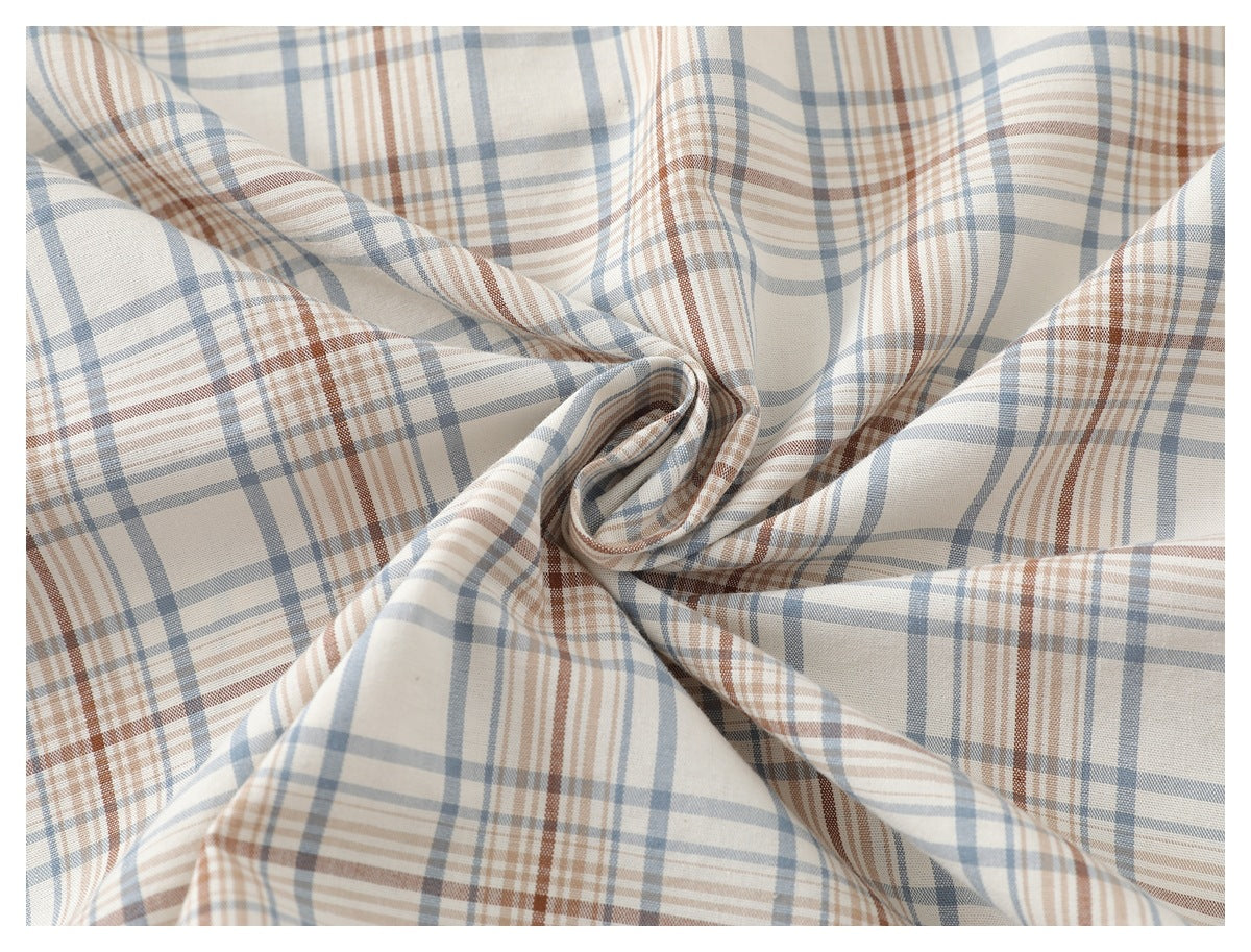 Close-up of ivory fabric with blue-gray and rust plaid, gathered to show its drape and pattern.