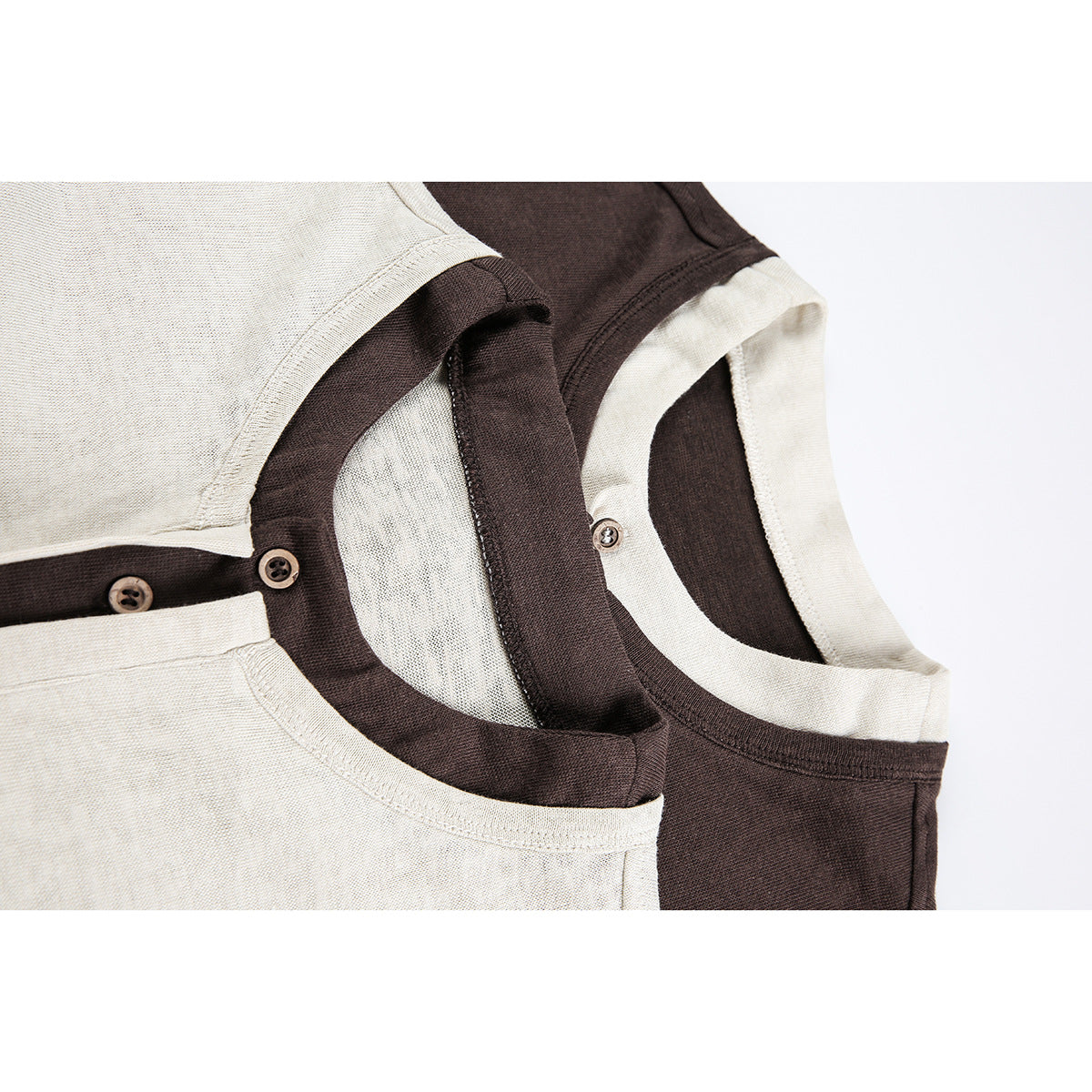 Close-up of overlapping cream and dark brown shirts showing contrasting crew necks and button plackets.
