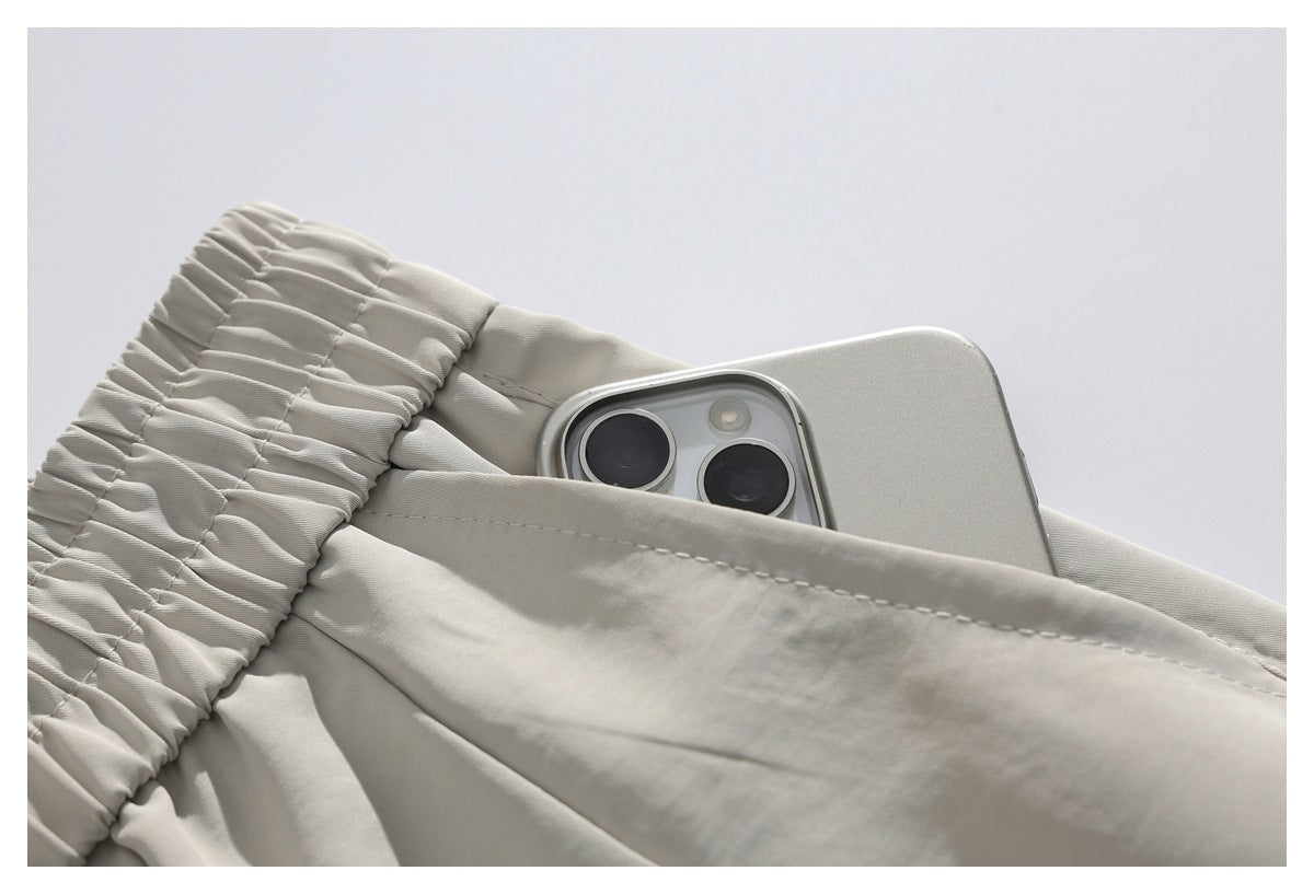Close-up of a pocket on light beige trousers, with a smartphone partly tucked inside.