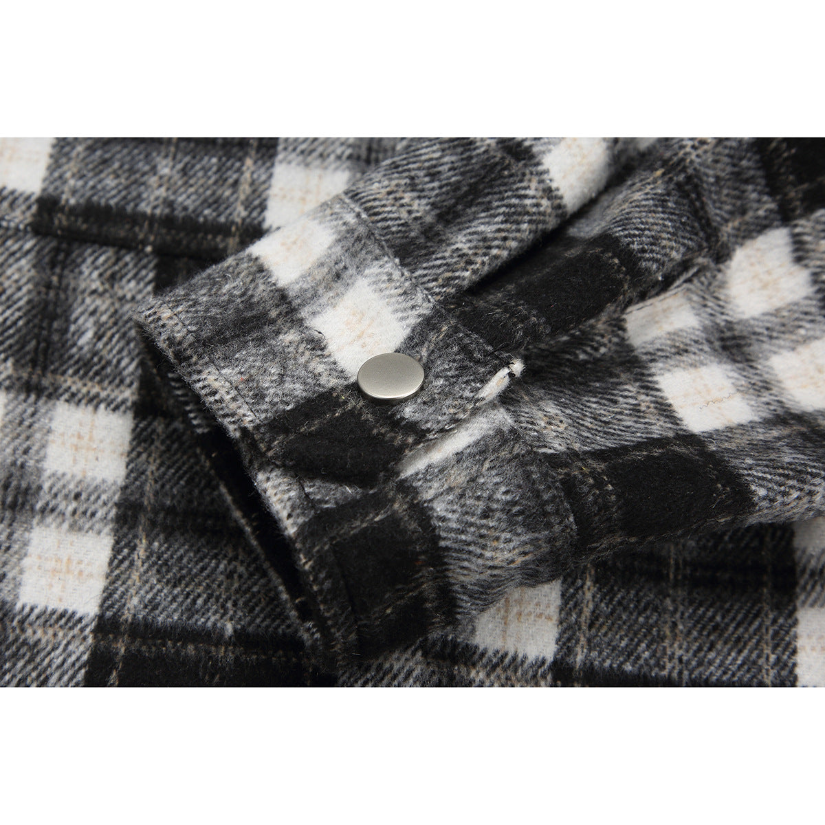 Close-up of a silver snap fastener on the black, gray, and white plaid fabric.