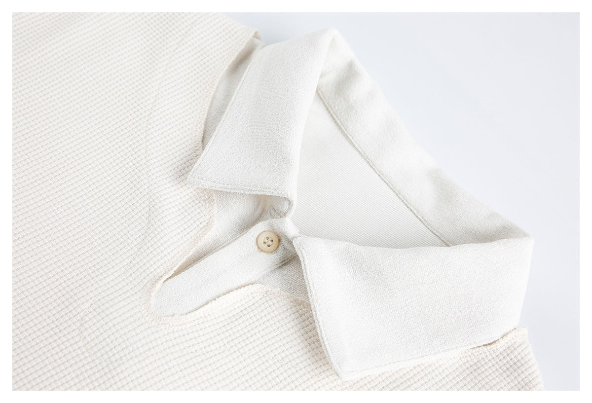 Close-up of an off-white waffle-knit polo collar, placket, and beige button.