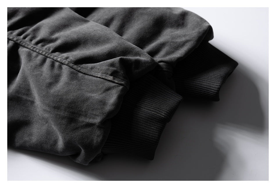 Close-up of a dark charcoal garment with a stitched seam and black ribbed cuff.