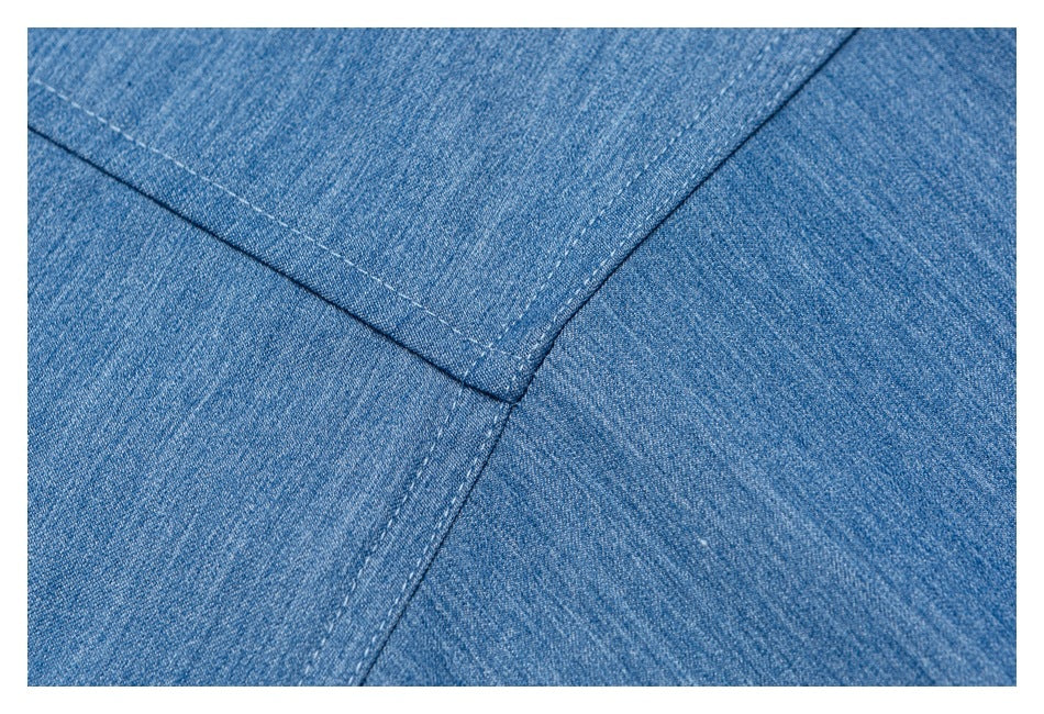 Close-up of blue denim panels meeting at a stitched seam junction.