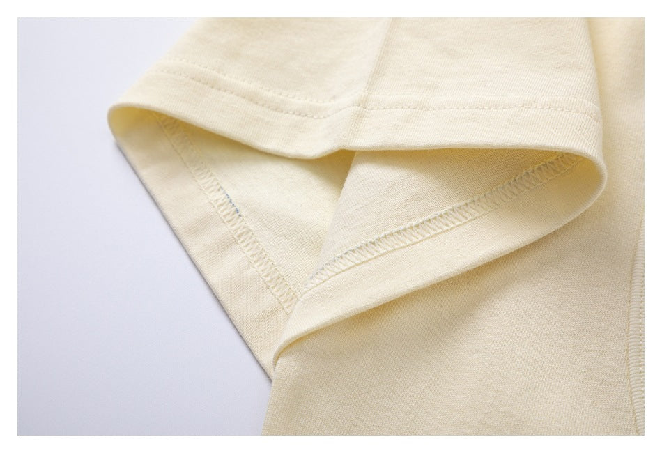 Close-up of an ivory garment edge showing the folded hem and inner overlock stitching.