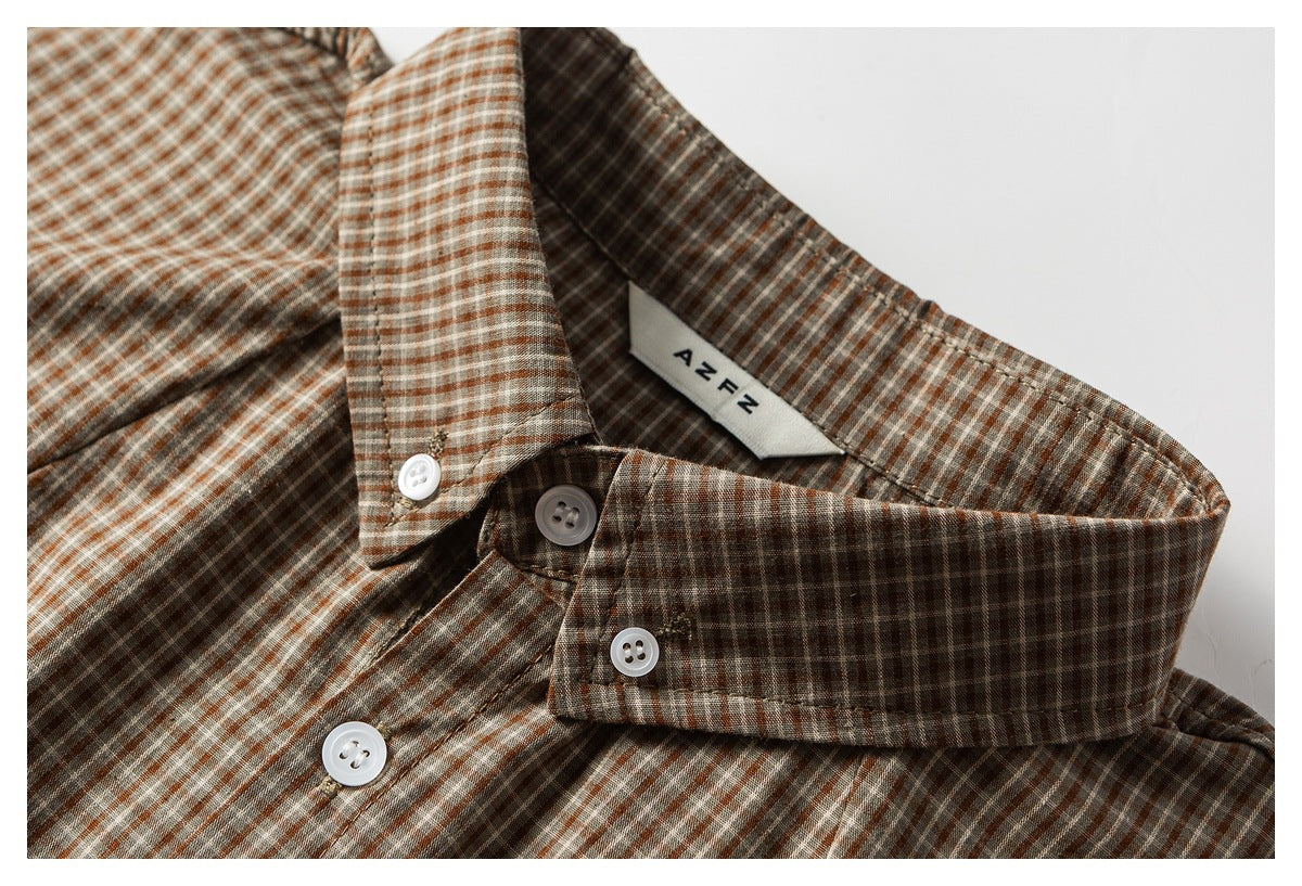 Close-up of a rust, gray, and white checked shirt collar, button placket, and inner neck label.