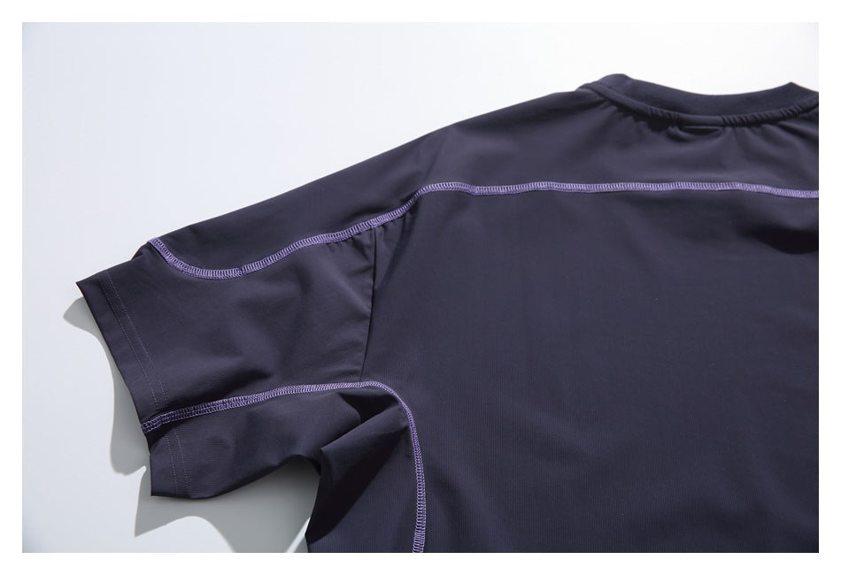 Close-up of a dark short-sleeve shirt showing the back shoulder and sleeve seams with purple stitching.