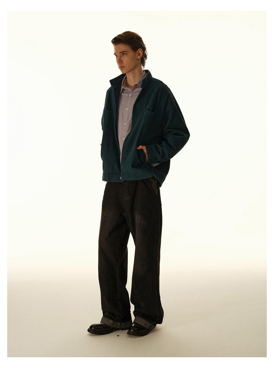 Three-quarter full-length view of a model in a dark teal jacket and loose black trousers.