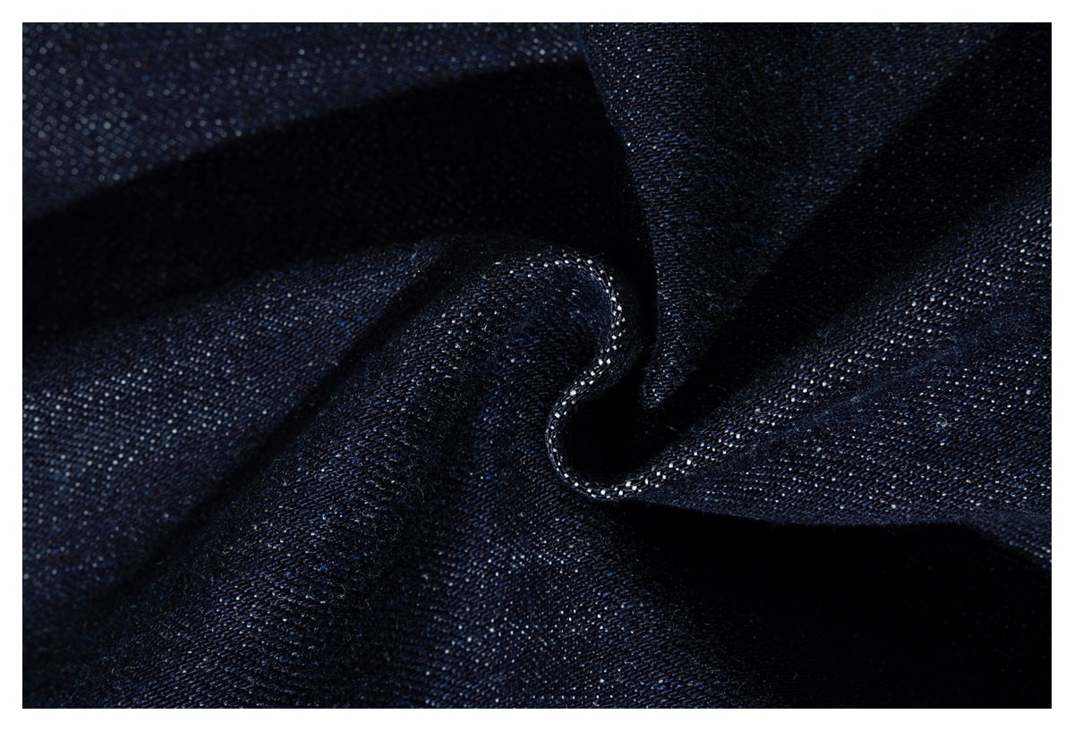 Close-up of dark indigo denim in soft folds, showing its woven texture and stitching.