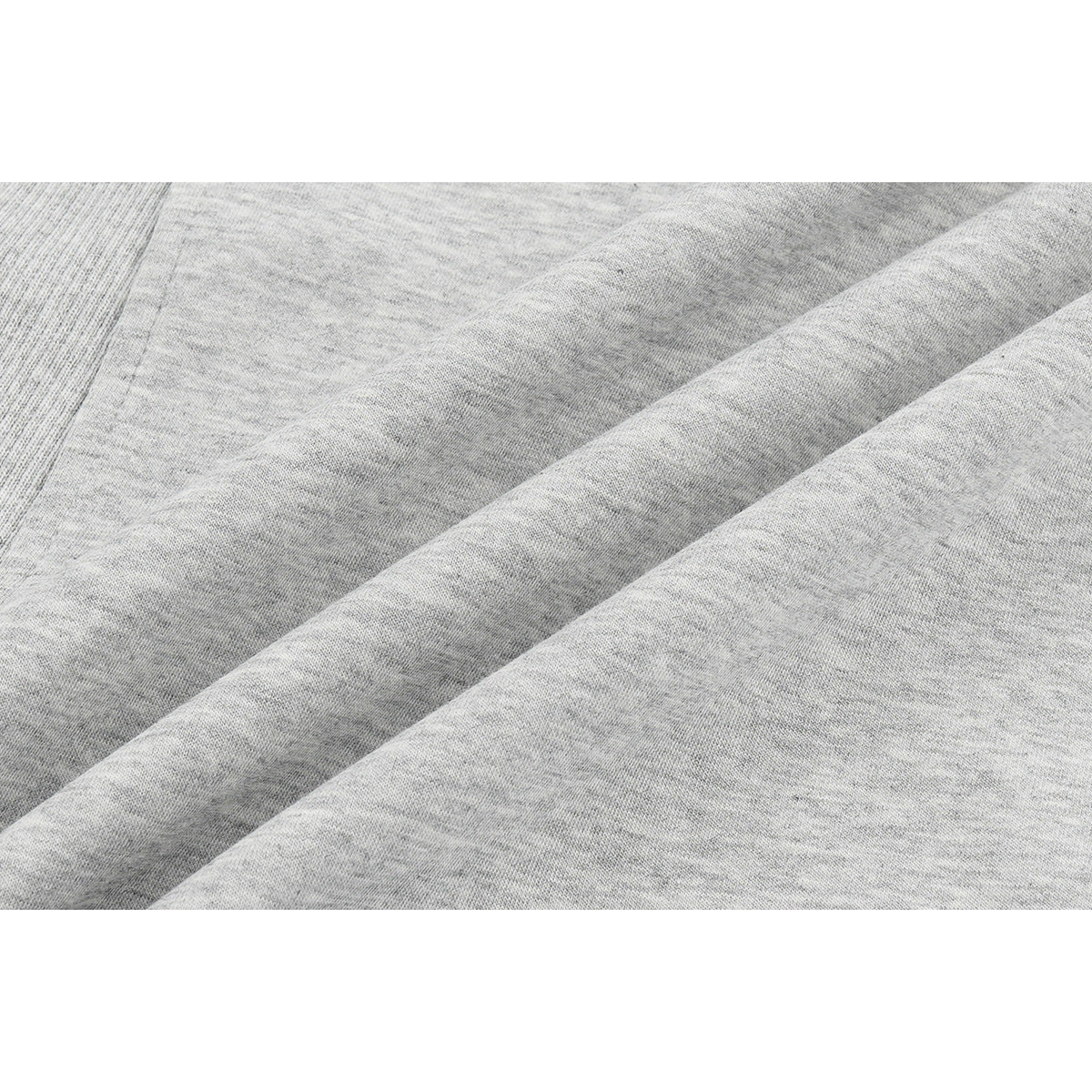 Close-up of heather gray fabric gathered into soft folds, with a ribbed seam at the edge.